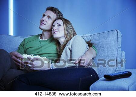Couple watching television on sofa View Large Photo Image Stock Photo - Couple watching television on sofa. Fotosearch