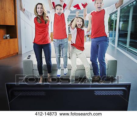 Family cheering in front of television in living room View Large Photo Image Stock Image - Family cheering in front of television in living room. Fotosearch