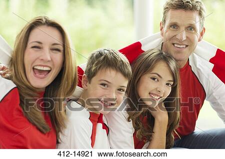 Family in sports jerseys cheering in living room View Large Photo Image Stock Image - Family in sports jerseys cheering in living room. Fotosearch