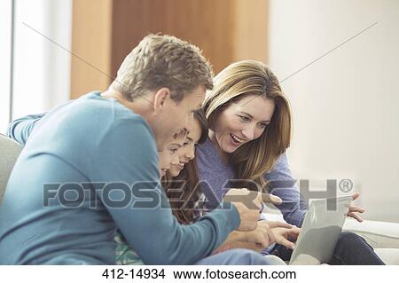 Family using laptop in living room View Large Photo Image Picture - Family using laptop in living room. Fotosearch