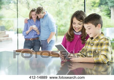 Stock Photo - Family using technology in kitchen. Fotosearch