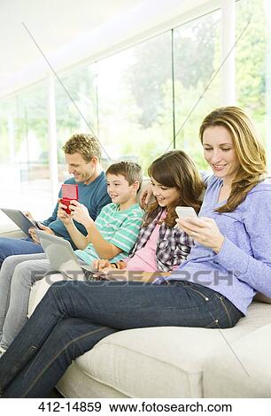 Family using technology on sofa View Large Photo Image Stock Photo - Family using technology on sofa. Fotosearch