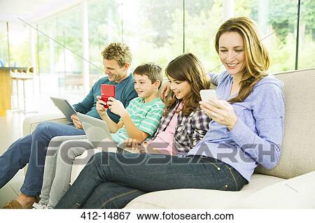 Family using technology on sofa View Large Photo Image Stock Photo - Family using technology on sofa. Fotosearch