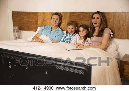 Family watching television in bed View Large Photo Image Stock Image - Family watching television in bed. Fotosearch