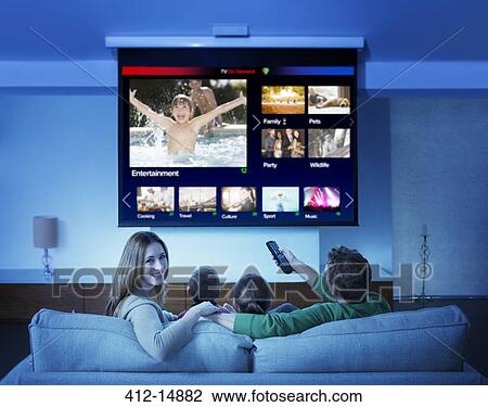 Stock Image - Family watching television in living room. Fotosearch