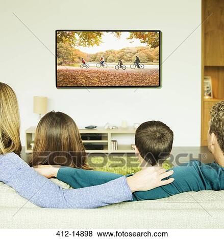 Stock Photo - Family watching television in living room. Fotosearch