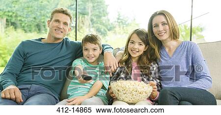 Family watching television in living room View Large Photo Image Stock Photography - Family watching television in living room. Fotosearch