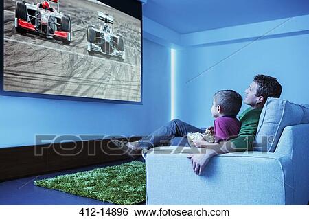 Father and son watching television in living room View Large Photo Image Stock Photograph - Father and son watching television in living room. Fotosearch