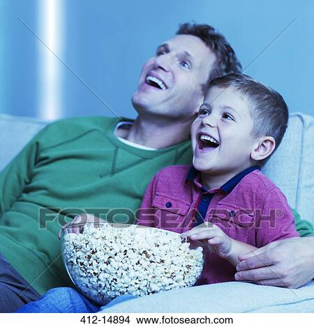 Father and son watching television on sofa View Large Photo Image Picture - Father and son watching television on sofa. Fotosearch
