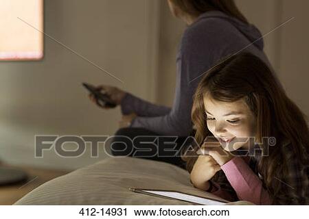 Girl using digital tablet on bed View Large Photo Image Stock Image - Girl using digital tablet on bed. Fotosearch