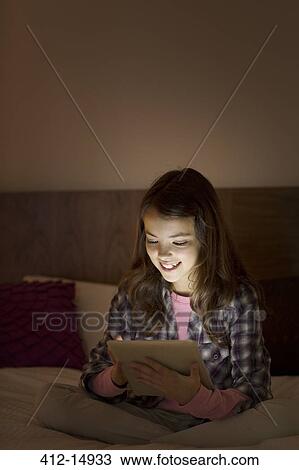 Girl using digital tablet on bed View Large Photo Image Stock Image - Girl using digital tablet on bed. Fotosearch