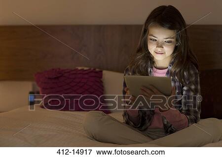 Girl using digital tablet on bed View Large Photo Image Stock Photo - Girl using digital tablet on bed. Fotosearch