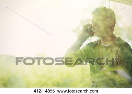 Man talking on cell phone at window View Large Photo Image Stock Photography - Man talking on cell phone at window. Fotosearch