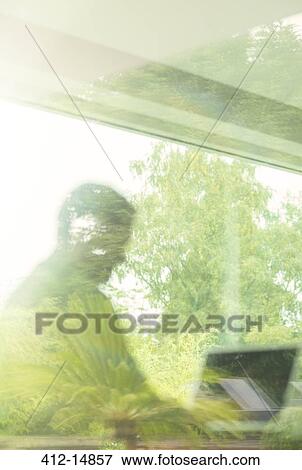 Man using laptop viewed through window View Large Photo Image Stock Photo - Man using laptop viewed through window. Fotosearch