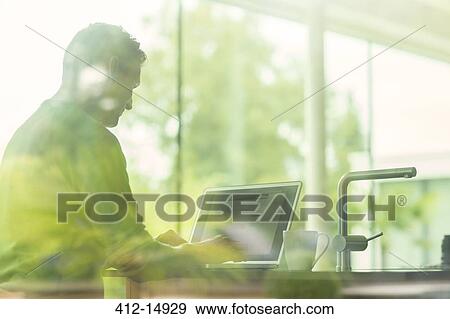 Man using laptop viewed through window View Large Photo Image Stock Photo - Man using laptop viewed through window. Fotosearch