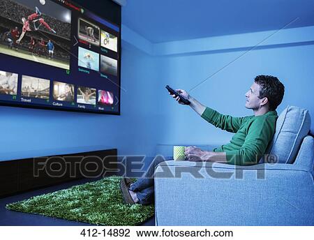 Man watching television in living room View Large Photo Image Stock Image - Man watching television in living room. Fotosearch
