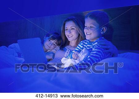 Mother and children using digital tablet in bed View Large Photo Image Stock Image - Mother and children using digital tablet in bed. Fotosearch