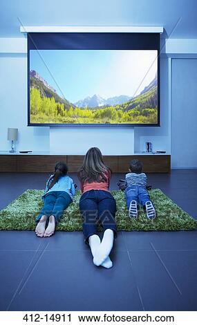 Mother and children watching television in living room View Large Photo Image Stock Image - Mother and children watching television in living room. Fotosearch