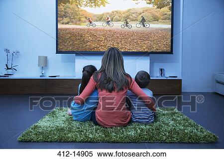 Mother and children watching television in living room View Large Photo Image Stock Photography - Mother and children watching television in living room. Fotosearch