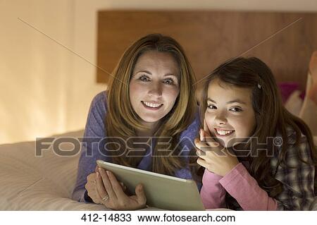 Mother and daughter using digital tablet on bed View Large Photo Image Stock Image - Mother and daughter using digital tablet on bed. Fotosearch