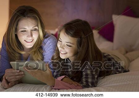 Mother and daughter using digital tablet on bed View Large Photo Image Stock Photo - Mother and daughter using digital tablet on bed. Fotosearch