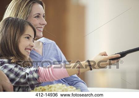 Mother and daughter watching television in living room View Large Photo Image Stock Photograph - Mother and daughter watching television in living room. Fotosearch