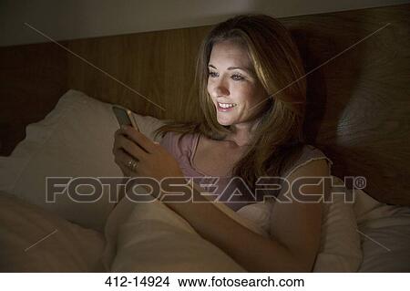 Woman using cell phone in bed View Large Photo Image Picture - Woman using cell phone in bed. Fotosearch