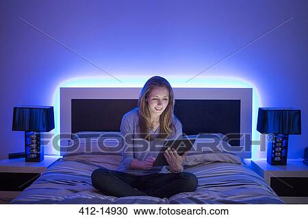 Woman using digital tablet on bed View Large Photo Image Stock Image - Woman using digital tablet on bed. Fotosearch