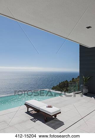 Lounge chair by infinity pool overlooking ocean View Large Photo Image Picture - Lounge chair by infinity pool overlooking ocean. Fotosearch