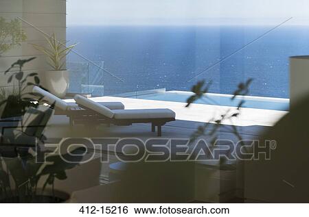 Lounge chairs and infinity pool overlooking ocean View Large Photo Image Stock Photograph - Lounge chairs and infinity pool overlooking ocean. Fotosearch