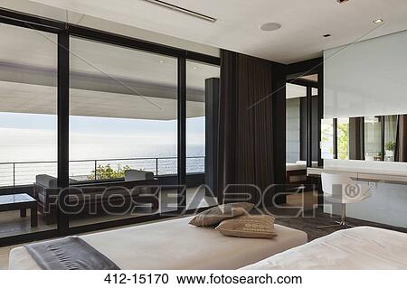 Stock Image - Modern bedroom and balcony overlooking ocean. Fotosearch