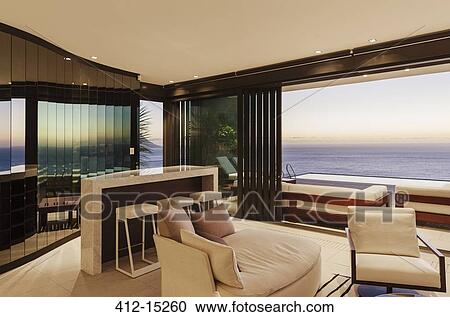 Modern living room and bar overlooking ocean at sunset View Large Photo Image Stock Image - Modern living room and bar overlooking ocean at sunset. Fotosearch