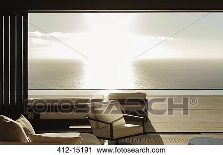 Modern living room overlooking ocean at sunset View Large Photo Image Stock Image - Modern living room overlooking ocean at sunset. Fotosearch