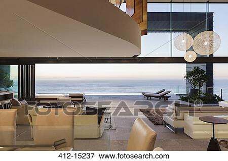 Modern living room overlooking ocean at sunset View Large Photo Image Stock Photo - Modern living room overlooking ocean at sunset. Fotosearch