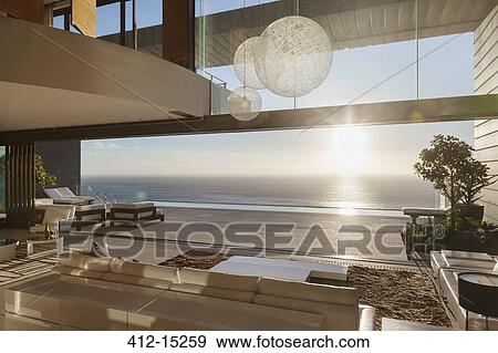 Modern living room overlooking ocean at sunset View Large Photo Image Stock Photo - Modern living room overlooking ocean at sunset. Fotosearch