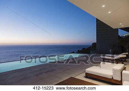 Modern patio and infinity pool overlooking ocean at sunset View Large Photo Image Stock Image - Modern patio and infinity pool overlooking ocean at sunset. Fotosearch