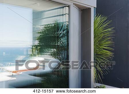 Stock Photo - Palm tree peeking around corner of modern house. Fotosearch