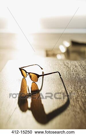 Sunglasses casting shadow on table View Large Photo Image Stock Image - Sunglasses casting shadow on table. Fotosearch