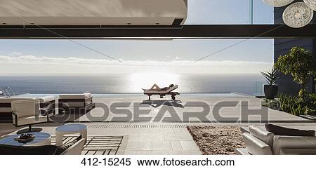 Woman sunbathing on lounge chair at poolside overlooking ocean View Large Photo Image Stock Photography - Woman sunbathing on lounge chair at poolside overlooking ocean. Fotosearch