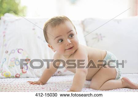 Stock Image - Baby boy crawling on sofa. Fotosearch