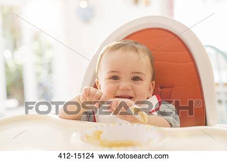 Baby boy eating in high chair View Large Photo Image Picture - Baby boy eating in high chair. Fotosearch