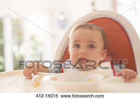 Stock Photography - Baby boy eating in high chair. Fotosearch