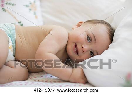 Stock Photo - Baby boy laying on bed. Fotosearch