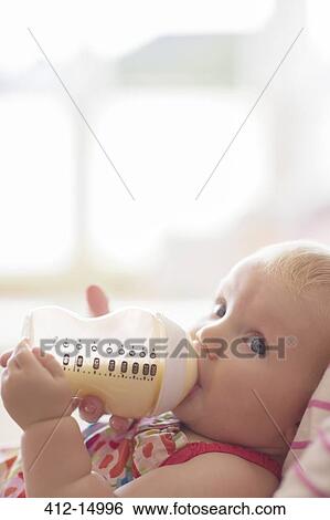 Stock Photograph - Baby girl drinking from bottle. Fotosearch