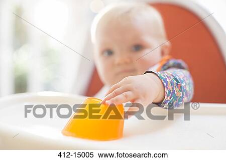 Stock Photography - Baby girl eating in high chair. Fotosearch