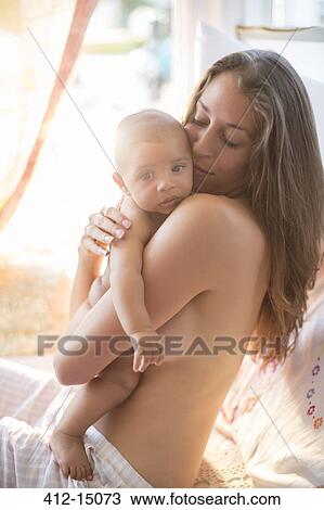 Stock Image - Bare chested mother holding baby boy. Fotosearch
