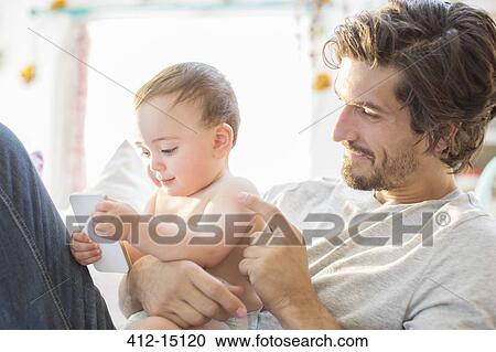 Stock Image - Father and baby boy playing with cell phone. Fotosearch