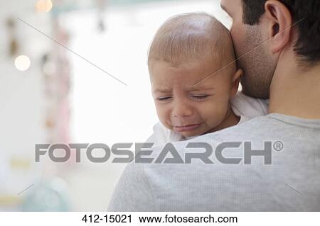 Stock Image - Father holding crying baby boy. Fotosearch