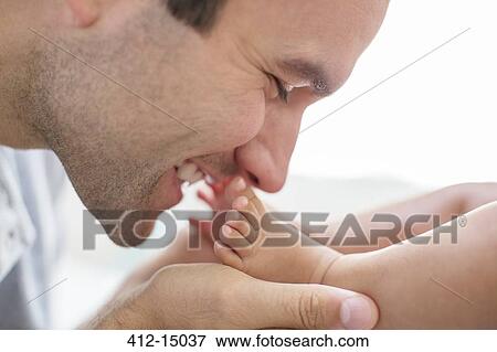 Stock Photo - Father kissing baby boy's feet. Fotosearch