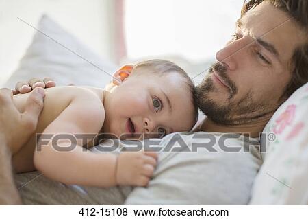Father laying with baby boy on bed View Large Photo Image Stock Photo - Father laying with baby boy on bed. Fotosearch